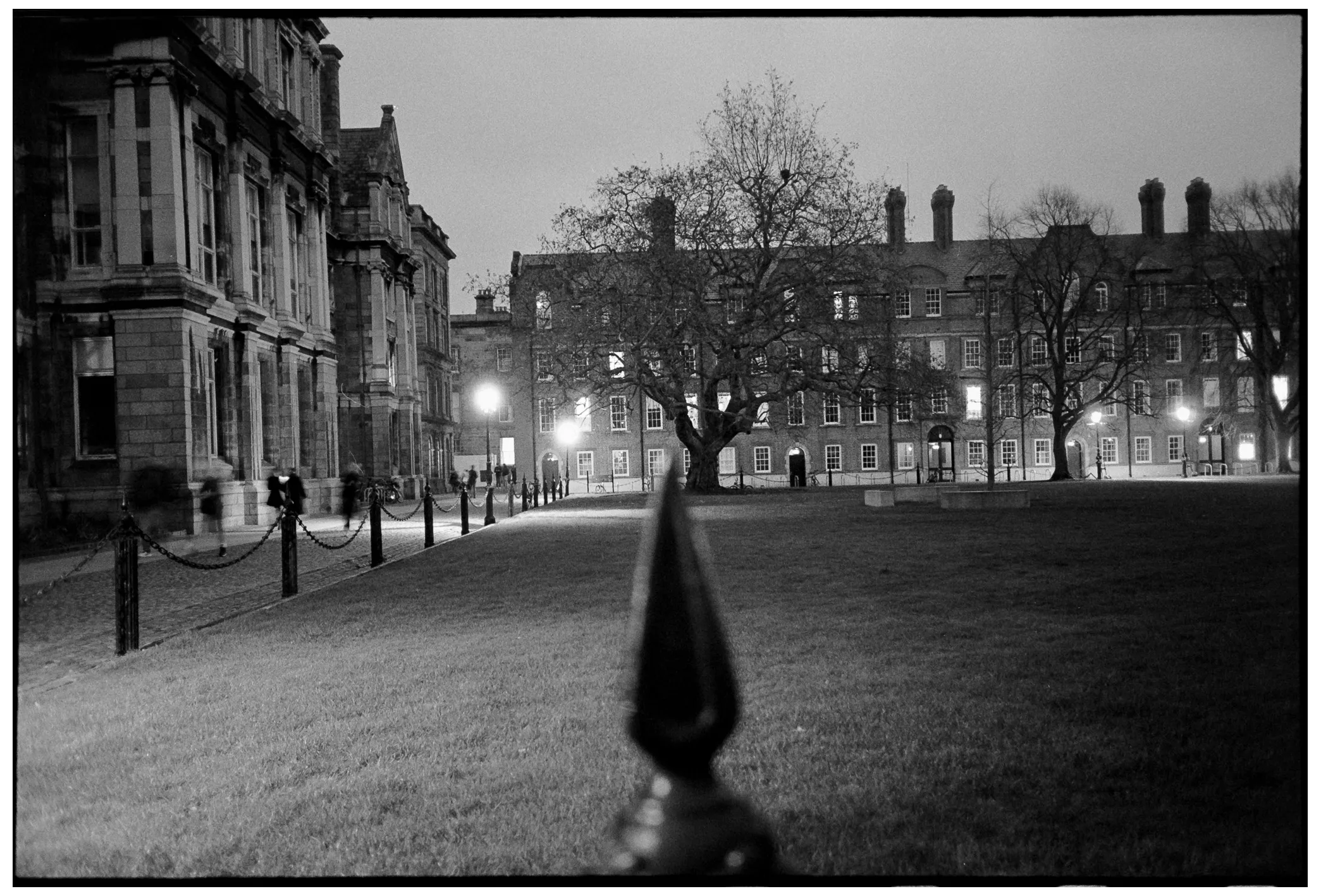 Night view of an illuminated university quad with blurred figures walking
