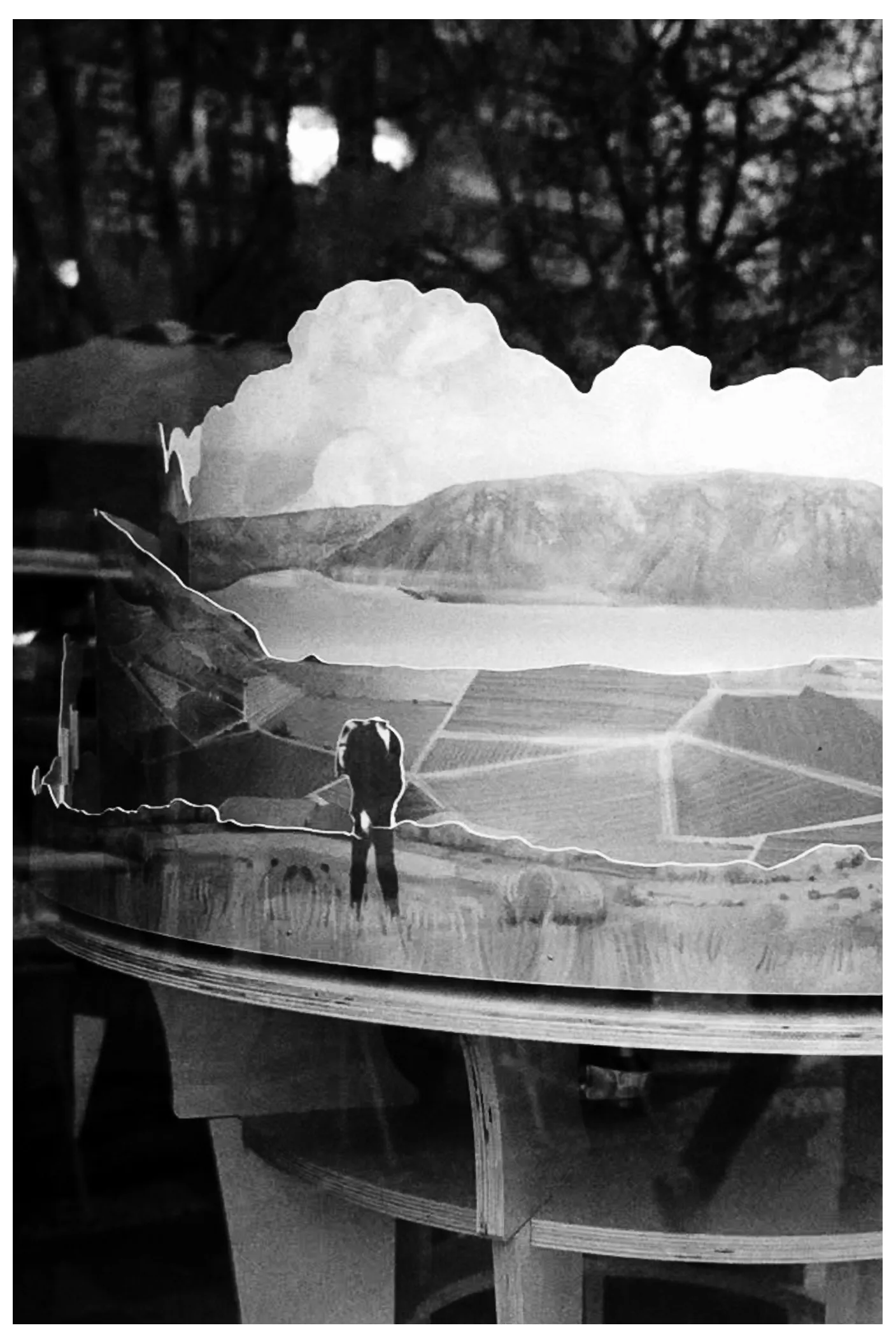 Double-exposure collage of a landscape and lone figure over a round table