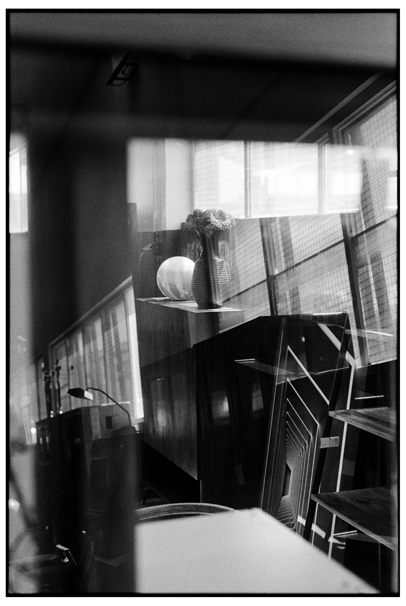 Layered window reflections over an interior with vases and furniture
