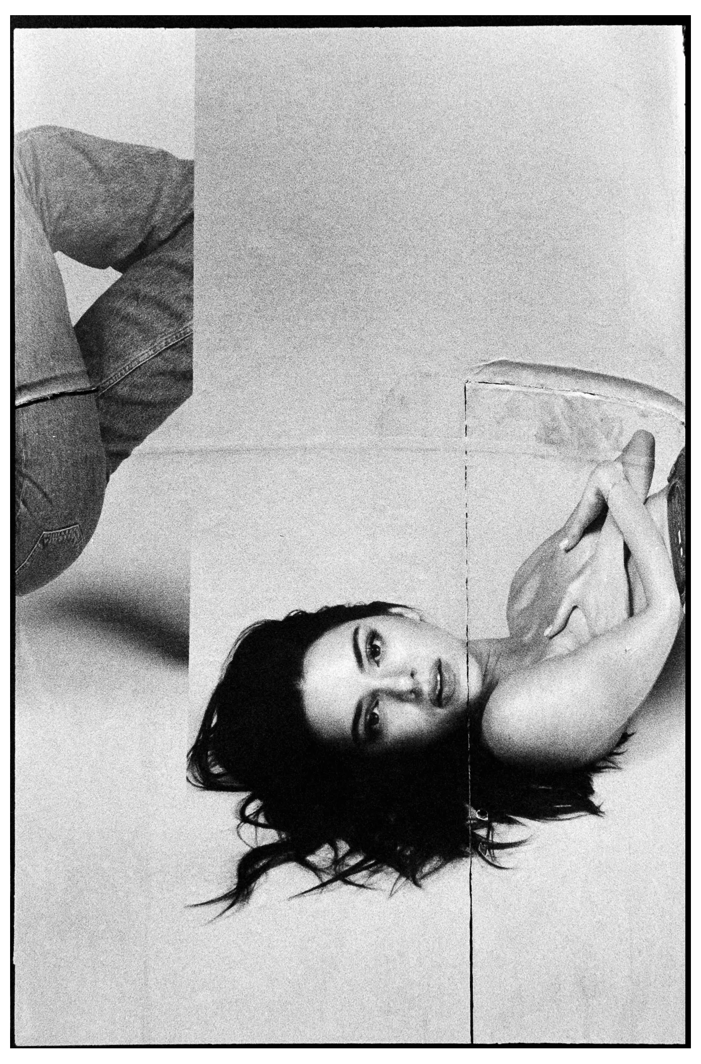 Portrait of a woman lying on her back, head tilted, hand near her face
